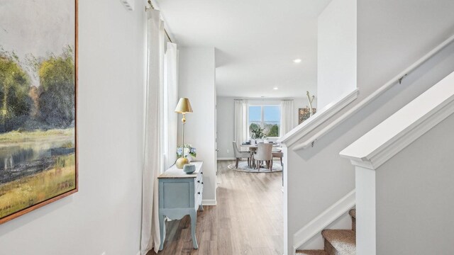 corridor featuring recessed lighting, wood finished floors, baseboards, and stairs