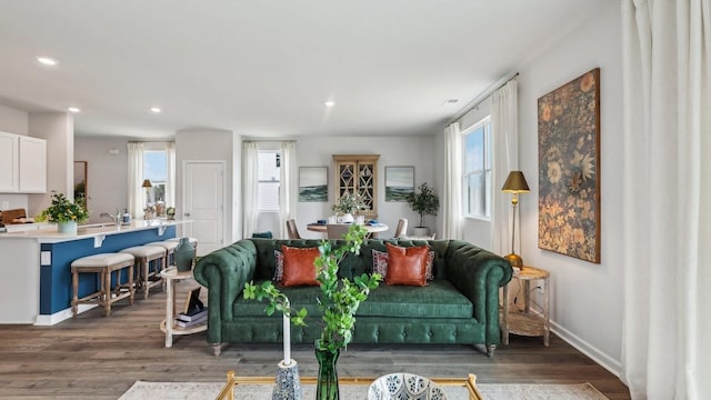 living area with baseboards, wood finished floors, and recessed lighting