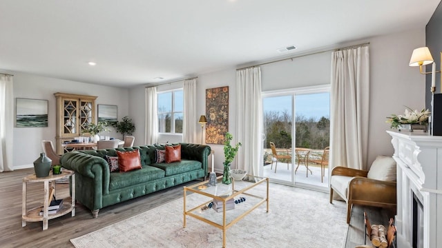 living room with recessed lighting, a fireplace, wood finished floors, visible vents, and baseboards