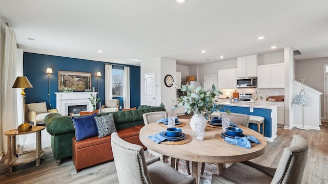 dining area with baseboards, light wood finished floors, a fireplace, and recessed lighting