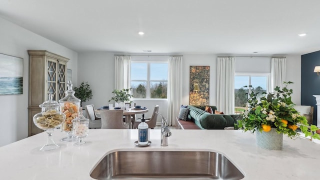 kitchen featuring open floor plan, light countertops, a sink, and recessed lighting