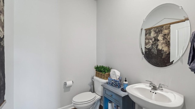 bathroom with toilet, baseboards, and a sink