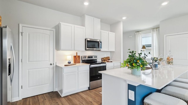 kitchen with white cabinets, appliances with stainless steel finishes, and a kitchen breakfast bar