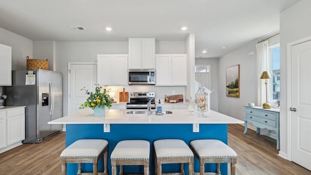 kitchen with light wood finished floors, visible vents, appliances with stainless steel finishes, and a breakfast bar