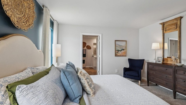 carpeted bedroom featuring ensuite bathroom and baseboards