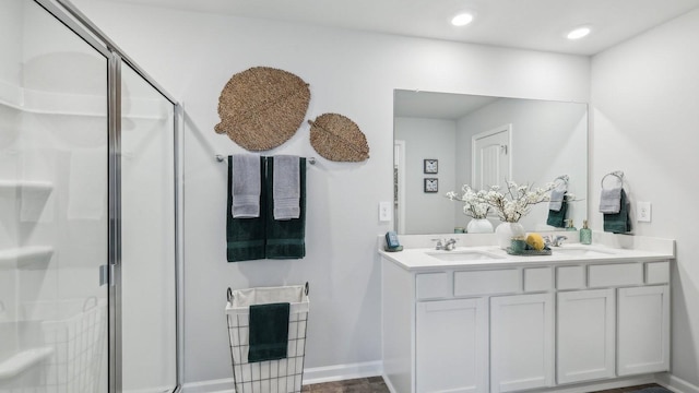 full bath with double vanity, a stall shower, baseboards, and a sink