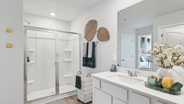 bathroom with wood finished floors, a shower stall, and vanity