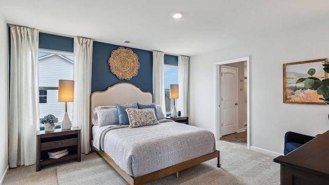 bedroom featuring light carpet, multiple windows, and baseboards