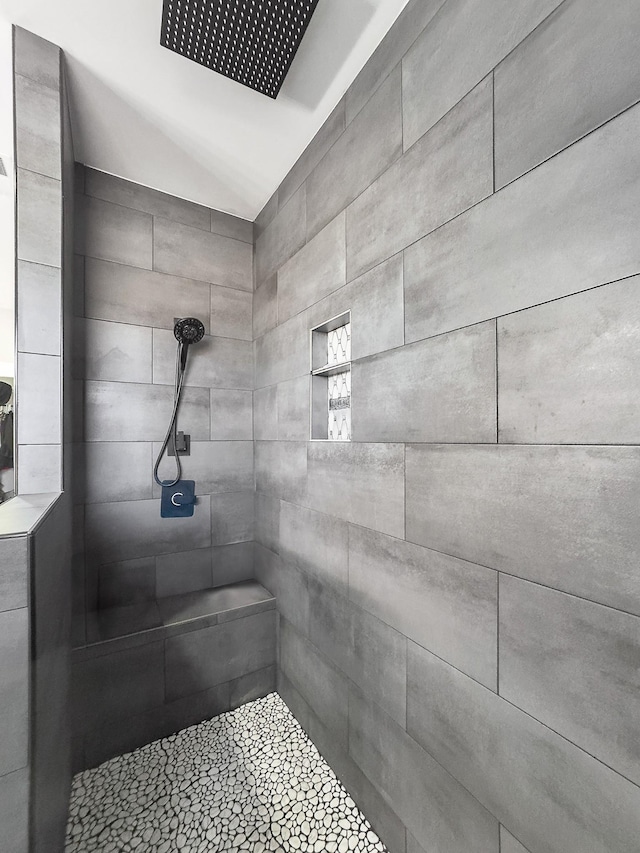 full bath featuring vaulted ceiling and a tile shower