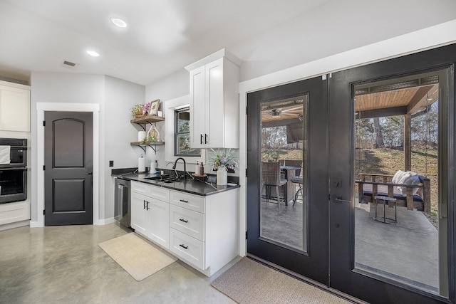 kitchen featuring white cabinets, french doors, stainless steel dishwasher, open shelves, and a sink