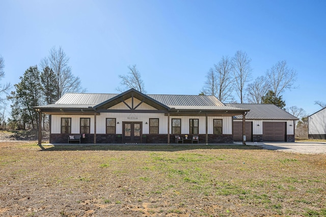 view of front of home with a garage, a front yard, french doors, and metal roof