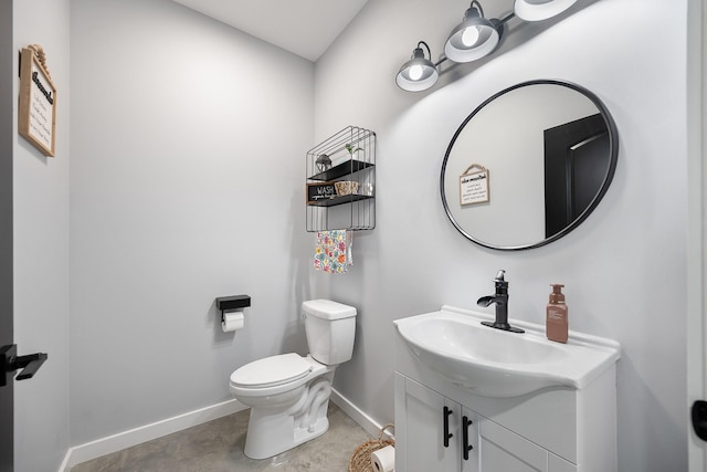 half bathroom with baseboards, vanity, and toilet