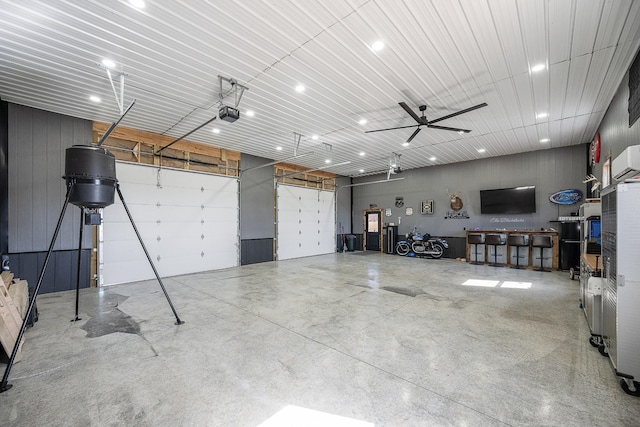 garage with a wall unit AC, a ceiling fan, and a garage door opener