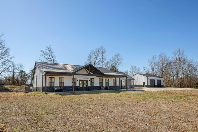 modern farmhouse style home with an outbuilding, metal roof, a garage, central AC, and a front lawn