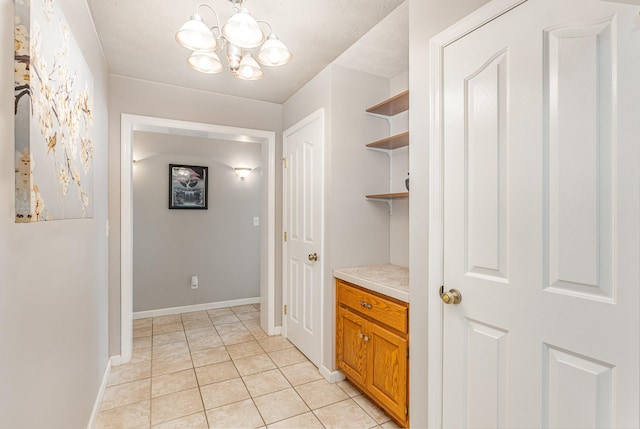 hallway with light tile patterned floors, a notable chandelier, and baseboards