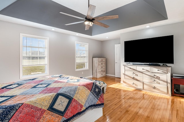 bedroom with recessed lighting, baseboards, a raised ceiling, and light wood finished floors