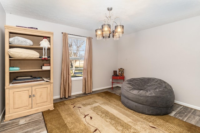 living area featuring baseboards, an inviting chandelier, and wood finished floors