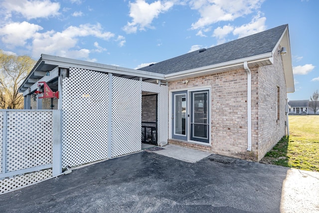 rear view of property with a patio, brick siding, and roof with shingles