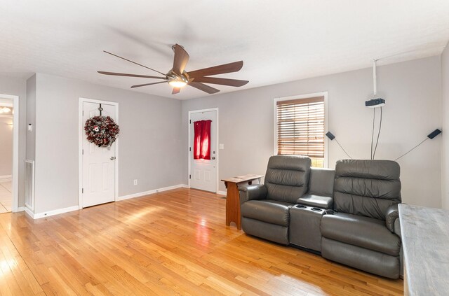 sitting room featuring light wood-style flooring, a ceiling fan, and baseboards