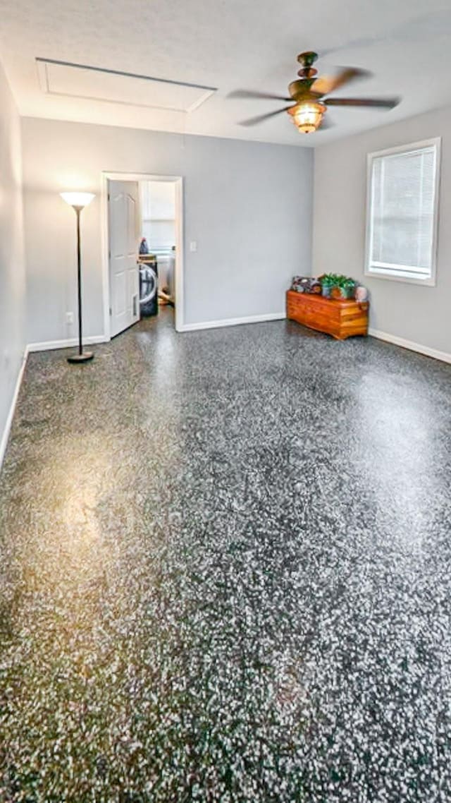 empty room featuring attic access, baseboards, and ceiling fan