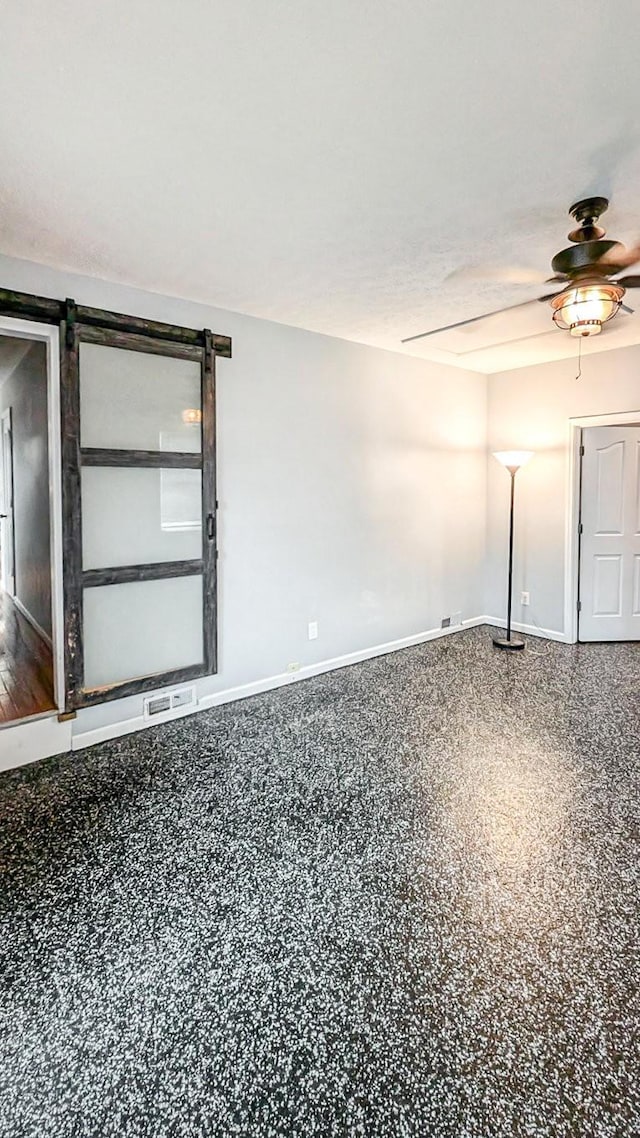 unfurnished room featuring a ceiling fan, speckled floor, visible vents, and baseboards