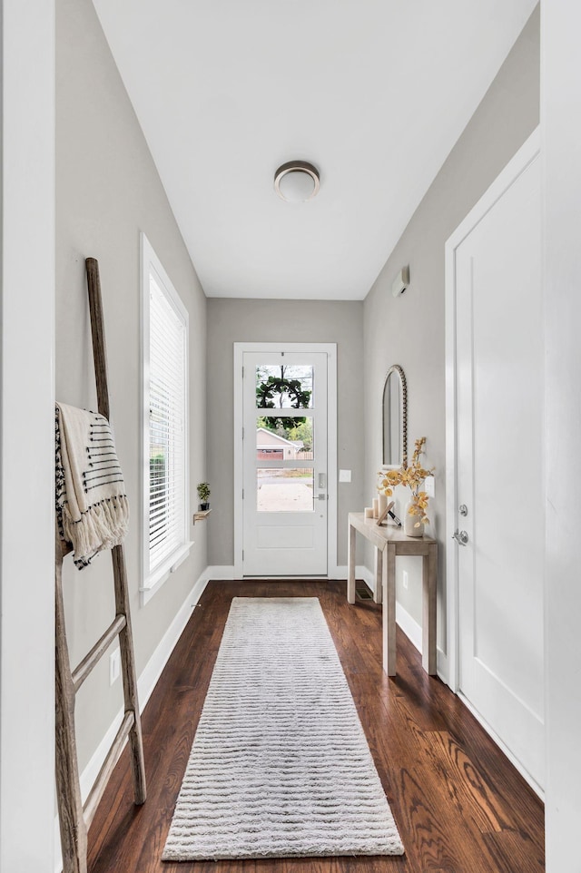 foyer entrance with dark wood-style flooring and baseboards