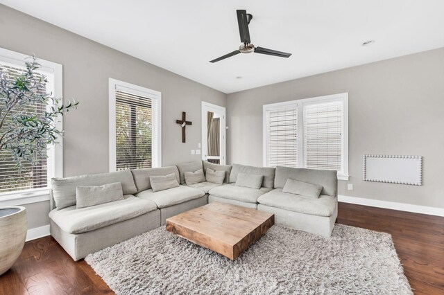 living area featuring dark wood-style floors, baseboards, and a healthy amount of sunlight