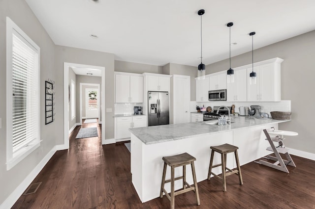 kitchen with a breakfast bar area, appliances with stainless steel finishes, a peninsula, a sink, and backsplash