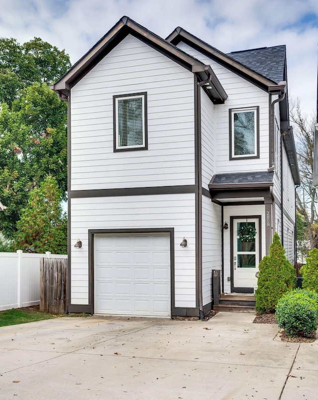 view of front of property featuring a garage, concrete driveway, fence, and a shingled roof