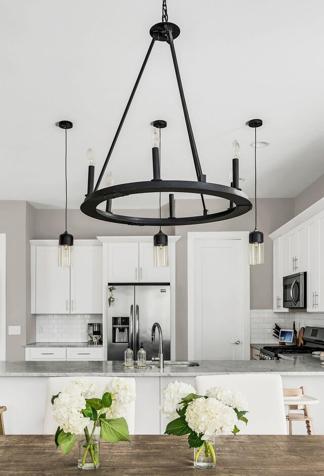 kitchen featuring stainless steel appliances, pendant lighting, white cabinetry, and tasteful backsplash