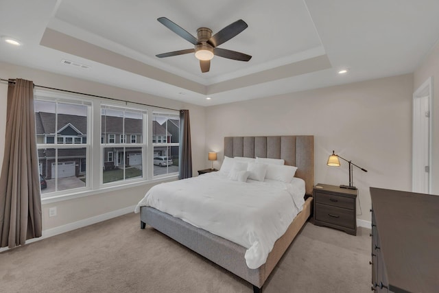 bedroom featuring baseboards, visible vents, a raised ceiling, and light colored carpet