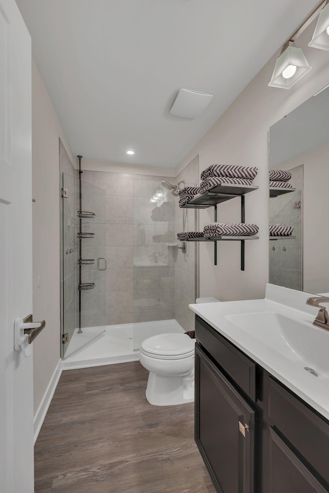 full bath featuring vanity, a shower stall, toilet, and wood finished floors