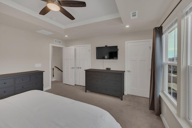 carpeted bedroom featuring visible vents, a tray ceiling, and recessed lighting