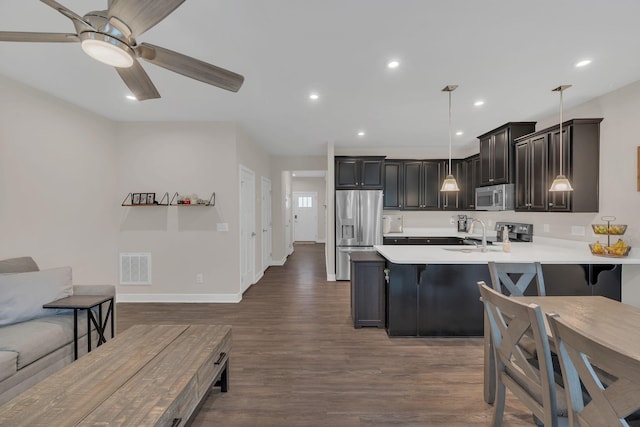 kitchen with a kitchen bar, appliances with stainless steel finishes, light countertops, and open floor plan