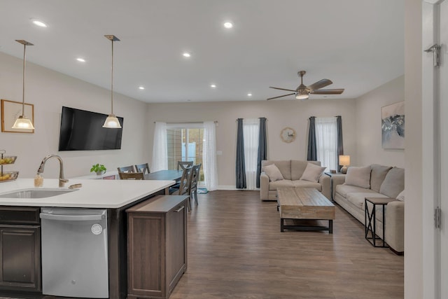 kitchen featuring dark wood finished floors, open floor plan, a sink, light countertops, and stainless steel dishwasher