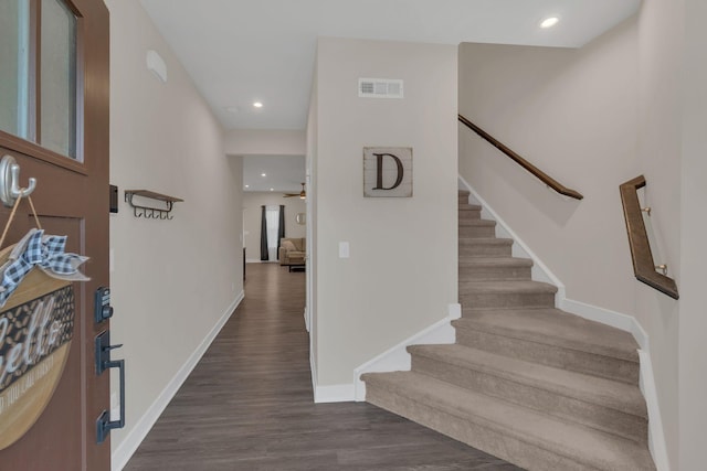 interior space with dark wood-type flooring, visible vents, stairway, and baseboards