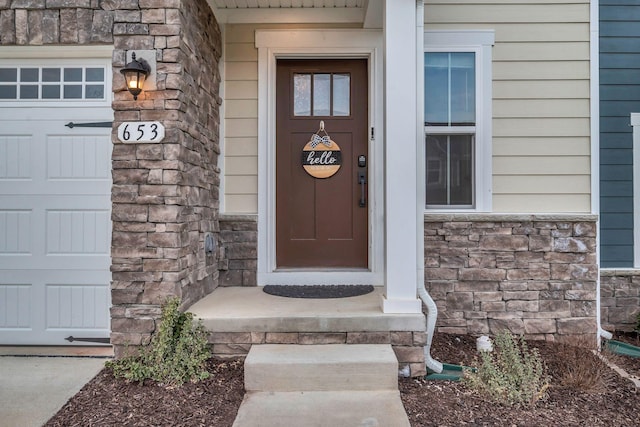 property entrance with a garage and stone siding