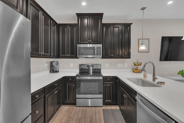 kitchen featuring light countertops, appliances with stainless steel finishes, a sink, and light wood-style flooring