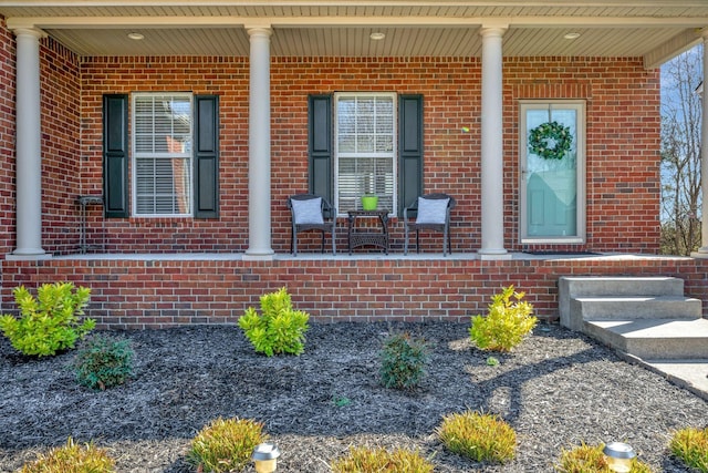 view of exterior entry with covered porch and brick siding