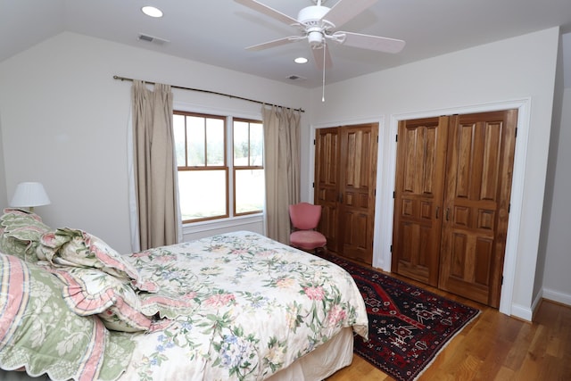 bedroom with visible vents, recessed lighting, two closets, and wood finished floors