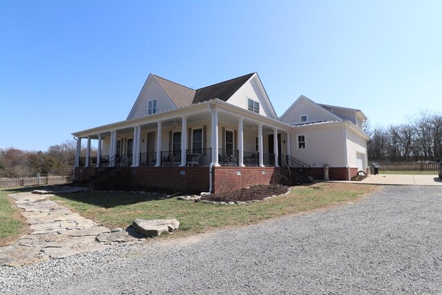 view of home's exterior with covered porch, driveway, and fence