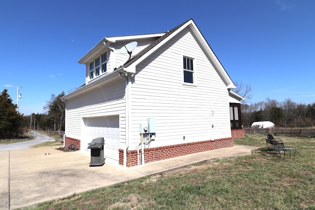 view of side of property featuring a yard, concrete driveway, an attached garage, and fence