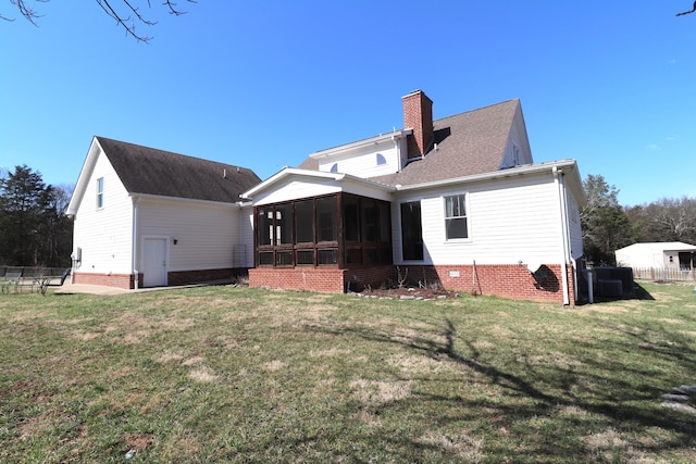 rear view of house featuring a lawn, a chimney, fence, and a sunroom