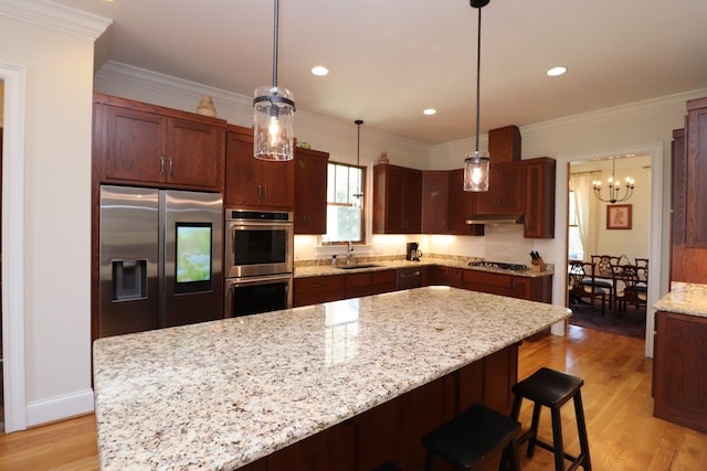 kitchen featuring a sink, light wood-style flooring, ornamental molding, and stainless steel appliances