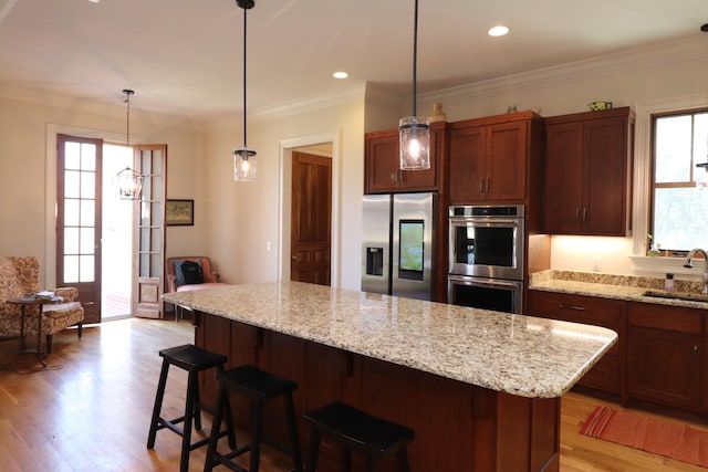 kitchen with crown molding, stainless steel appliances, light wood-type flooring, and a sink