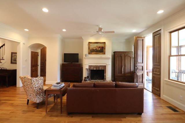 living room with ornamental molding, arched walkways, visible vents, and ceiling fan