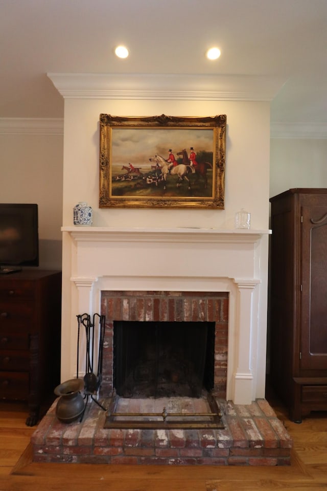 details featuring recessed lighting, wood finished floors, a brick fireplace, and ornamental molding