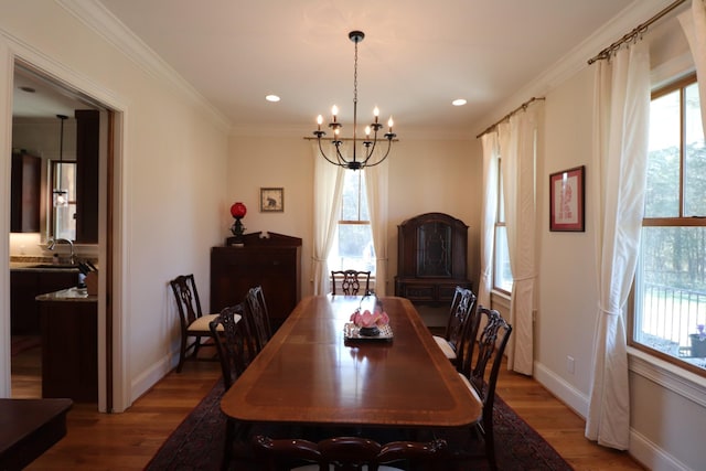 dining room with a notable chandelier, wood finished floors, recessed lighting, crown molding, and baseboards