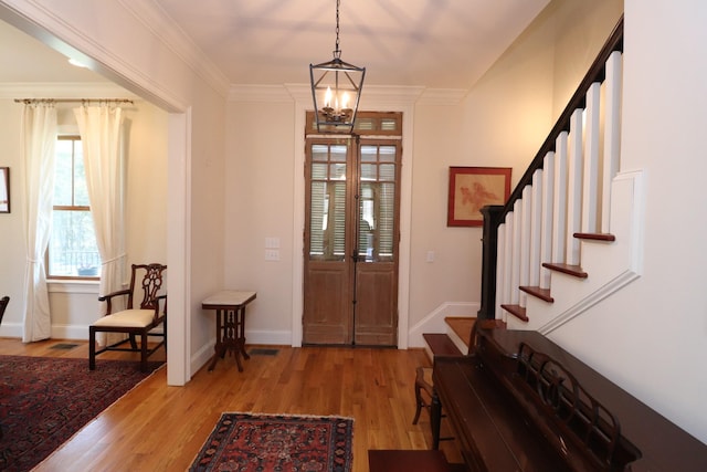 foyer with light wood-type flooring, baseboards, ornamental molding, and stairs