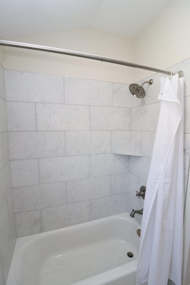 full bath featuring shower / tub combo with curtain and vaulted ceiling